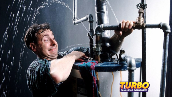 A man tries to fix a leaking pipe spraying water in multiple directions, highlighting the urgency of plumbing emergencies; "Turbo Plumbing Solutions" logo is visible in the corner.