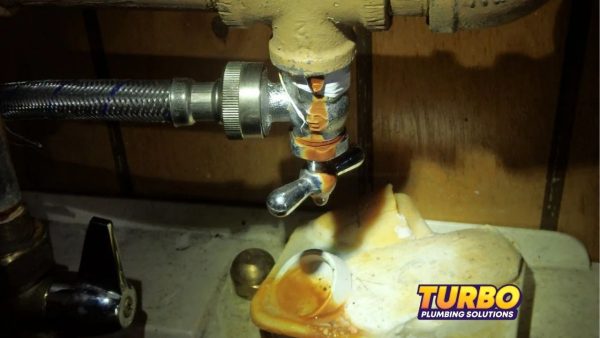 A rusty, leaking shut-off valve with water dripping onto a stained surface highlights common summer plumbing problems. The Turbo Plumbing Solutions logo is visible in the lower right corner.